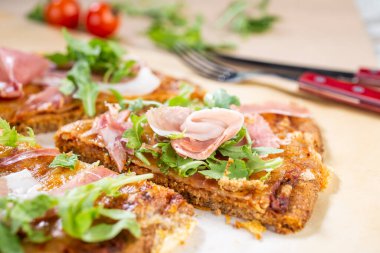 Arugula, prosciutto ve vişneli domatesli sağlıklı kabaklı pizza.