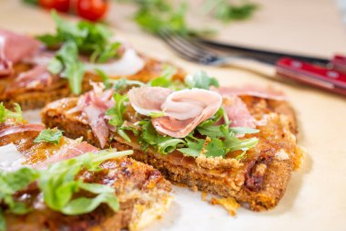 Arugula, prosciutto ve vişneli domatesli sağlıklı kabaklı pizza.