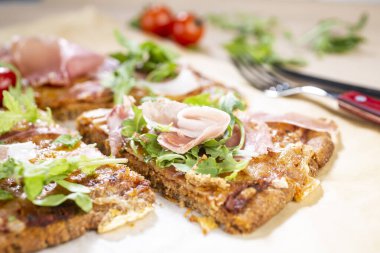 Arugula, prosciutto ve vişneli domatesli sağlıklı kabaklı pizza.