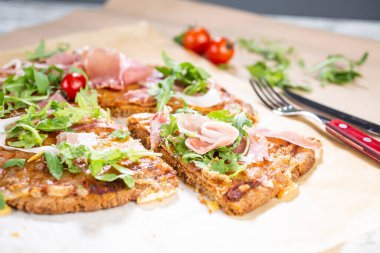 Arugula, prosciutto ve vişneli domatesli sağlıklı kabaklı pizza.