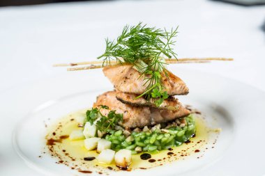 Salmon fillet served on green risotto with spinach and garnished with dill.