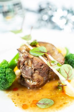 Zarifçe sunulan biftek fileto, otlarla süslenmiş ve sebze ve sosla servis edilmiş..