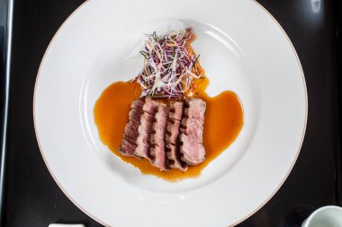 Dilimlenmiş et ve sebze salatası içeren kaplanmış yemek.