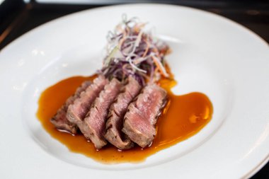 Sos ve salata serpiştirilmiş bir tabak et.