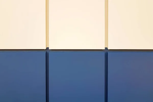 Close-up wall tiles in solid beige and dark blue without pattern laid out in neat even row on the facade of the building in daylight. Background with copy space for design and decoration. Mobile Photo