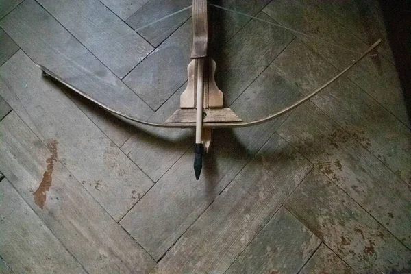 Crossbow and arrow view from top on a wood background
