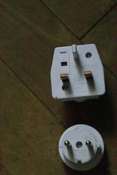 UK and EU plug adapter top view on wood background with copy space