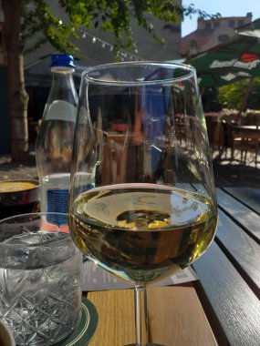 Beyaz şarap kadehi. Arka tarafta su şişesi ve cam var.