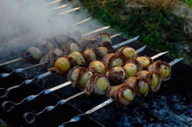 Kaynamış patatesler en taze pastırmaya sarılıp ızgarada açık ateşte pişirildi. Koyu kahverengi ahşap bir arka planda safran ve roka ile siyah bir mat tabağında servis edilir..