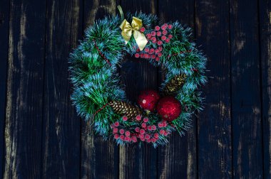 Yeşil Noel çelengi koni ve dekoratif böğürtlen ile koyu yanık ahşap bir arka planda izole edilir. Noel kompozisyonu. Kış renkli arkaplan.