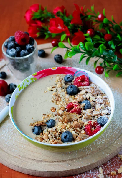 American breakfast. Cereal flakes boiled in milk with a hint of vanilla, decorated with forest fruits and shredded nuts. A nutritious breakfast, especially for children. Spring composition. Side view.