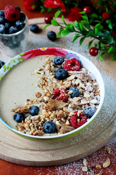 American breakfast. Cereal flakes boiled in milk with a hint of vanilla, decorated with forest fruits and shredded nuts. A nutritious breakfast, especially for children. Spring composition. Side view.