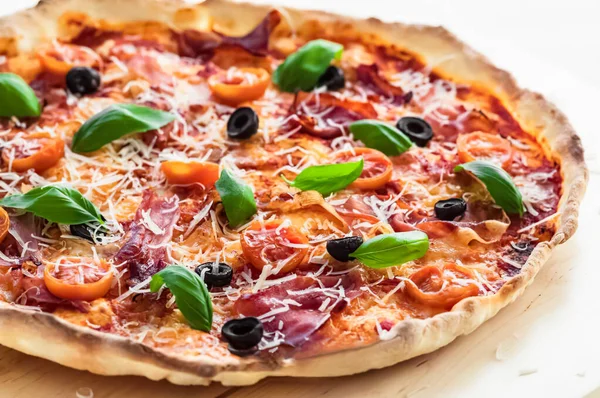 Prosciutto Pizza on a thin crust. Close-up, baked in a wood-fired pizza oven.  Italian cuisine. Gourmet meal.