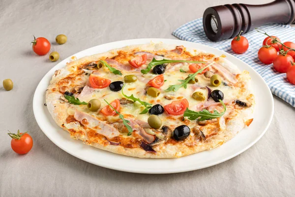 Tasty Capricciosa pizza decorated with green olives and cherry tomatoes. Perfect for background or menu use. Italian cuisine. Close-up, baked in a wood-fired pizza oven.  Italian cuisine. Gourmet meal.