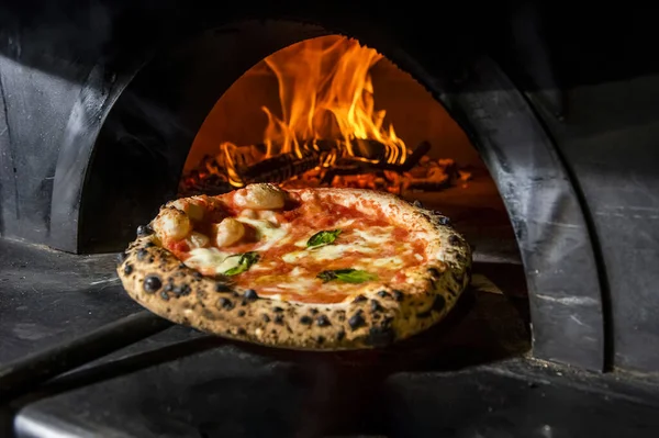 A Margarita pizza straight from a wood-fired oven. Close-up, baked in a wood-fired pizza oven. Italian cuisine. Rustic style. Culinary and restaurant concept.