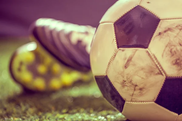 Yeşil çimlerin üzerinde futbol ayakkabıları ve futbol