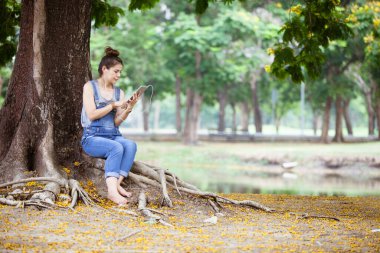 Dışarıda kulaklıklı tablet kullanan bir kadın.
