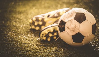 Yeşil çimlerin üzerinde futbol ayakkabıları ve futbol