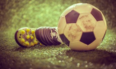 Yeşil çimlerin üzerinde futbol ayakkabıları ve futbol