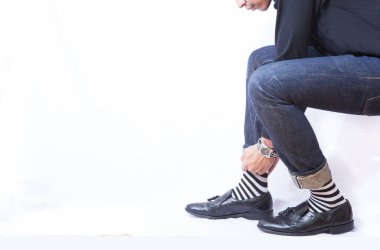 Beyaz arka planda kot pantolonlu deri ayakkabılar.