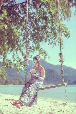 Kadın plajda dokunmatik tablet teknolojisi kullanıyor.