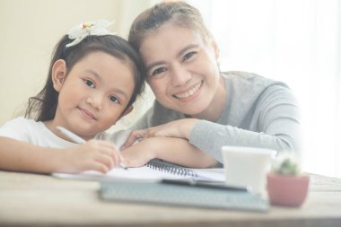 Anne, kızına ev ödevlerinde yardım ediyor.