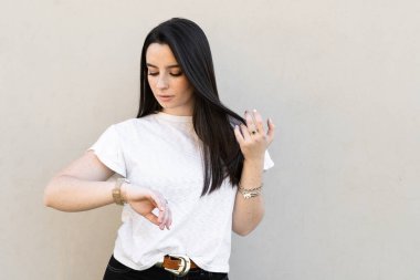 Genç siyah saçlı kadın saatine bakıyor. 