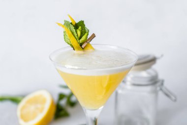 Martini bardağında nane ve limon garnitürlü sarı kokteyl..  