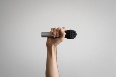Gri bir mikrofon tutarak elini kaldırdı. Protesto ve sesini yükseltme kavramı. 