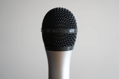 Beyaz arkaplanda gümüş bir mikrofonun yakın plan görüntüsü