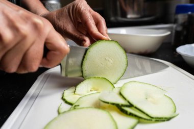 Şef kabak dilimleri kesiyor. Yan görünüm.