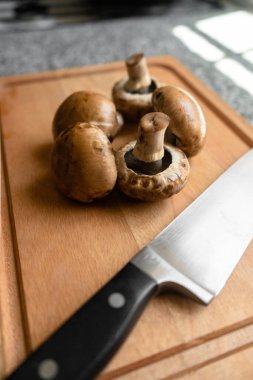 Kesme tahtasındaki mutfak bıçağıyla dikey mantar vuruşu.