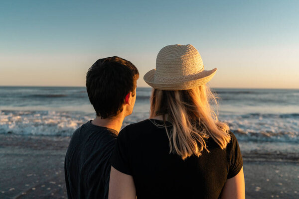 Young couple in love on the beach watching the sunset.