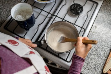 Evde beşamel sosu pişiren kadın manzarası.