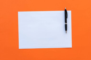 Turuncu arka planda tükenmez kalemle boş bir sayfa.