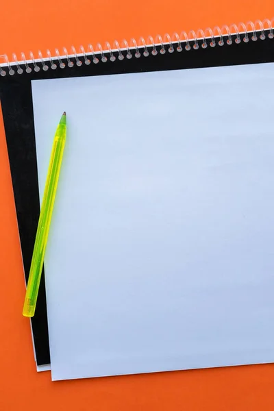 ノートとオレンジの背景にペンで空白のシートの垂直ショット — ストック写真