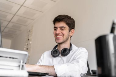 Ofiste laptopuyla çalışan genç adam.