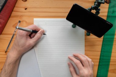 Solak kişi çevrimiçi derslerden notlar alıyor. Üst görünüm.
