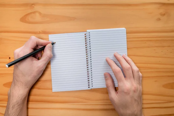 Left-handed person taking notes in a personal notebook or diary.