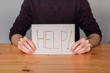 Yardım isteyen, elinde bir tabela tutan tanınmamış biri. 