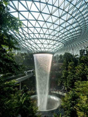 Güneş, Changi Singapur Havaalanı Mücevher Terminali 4 'ün kalbindeki şelaleden yansıyor.