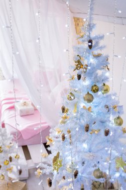 Noel odasının içi: dört posterli yatak ve beyaz Noel ağaçları. Pembe ve altın rengi Noel süsleri