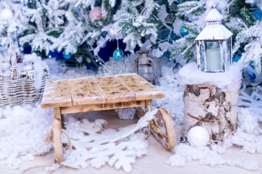 Noel süsleri. Beyaz Noel ağaçlarının arasında, karda çocukların ahşap kızağı.