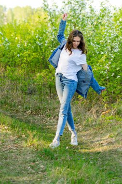 Bahar yürüyüşü. Bir kız çiçek açan bir elma bahçesinde yürüyor.