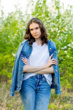 Bahar yürüyüşü. Bir kız çiçek açan bir elma bahçesinde yürüyor.