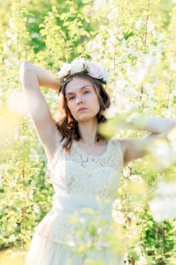 Çiçekli bir çelengin içindeki güzel bir kız çiçek açan elma ağaçlarının arasında.