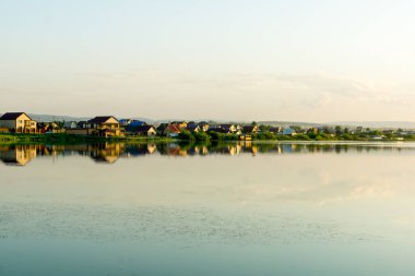 Gölde sıcak, güneşli bir akşam. Köyün gölünde gün batımı. Etrafı kuyruk ve söğüt ağaçlarıyla çevrili..