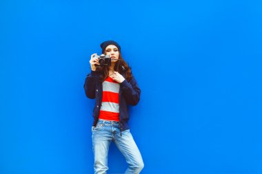 Arka planda fotoğraf makinesi olan güzel bir hippi kızın portresi mavi duvarı oluşturur.