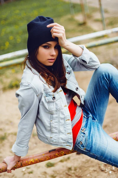 Портрет красивої дівчини-хіпстера, що сидить у капелюсі в парку — стокове фото