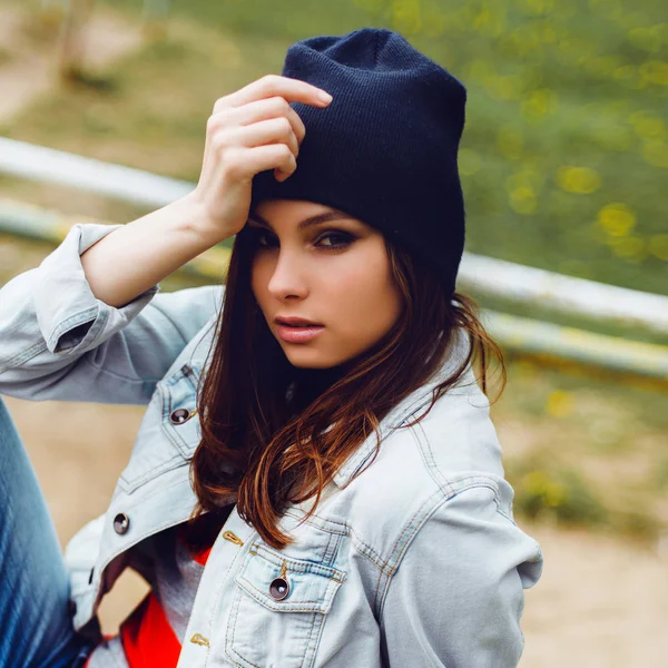 Portrait of a beautiful hipster girl sitting in hat at the park — Stock Photo, Image